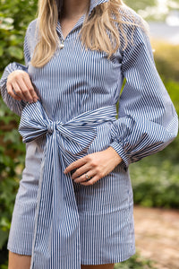 Woman wearing a blue and white striped dress with a blurred natural background